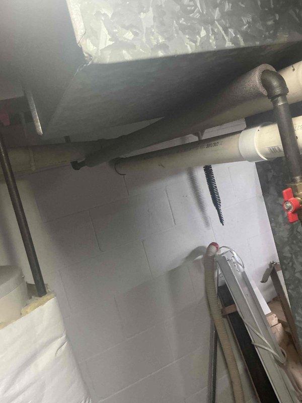 Conducted assessment of residential HVAC system for duct cleaning estimate. Inspected utility area containing insulated ductwork, PVC ventilation piping, and central furnace unit. Evaluated galvanized metal plenum and air distribution system for potential cleaning requirements, noting visible condition of connections and ventilation components.