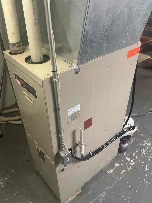 Conducted assessment of residential HVAC system for duct cleaning estimate. Inspected utility area containing insulated ductwork, PVC ventilation piping, and central furnace unit. Evaluated galvanized metal plenum and air distribution system for potential cleaning requirements, noting visible condition of connections and ventilation components.