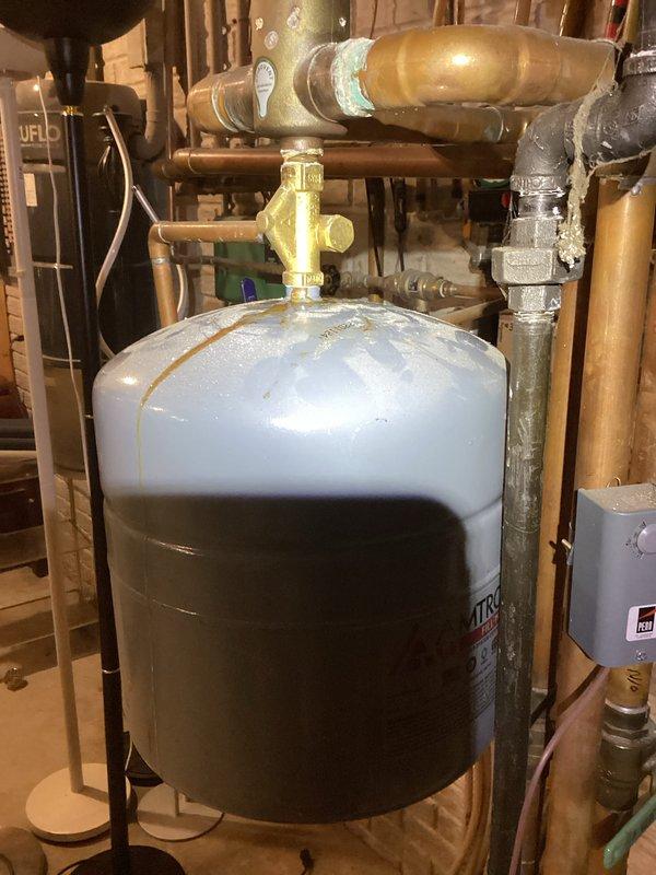 Inspected Amtrol expansion tank (Model T10) showing signs of condensation on exterior surface. System appears to have properly installed components with some oxidation noted at pipe joints. Visual assessment of copper piping network and valves indicated normal operational condition despite evidence of previous repairs.