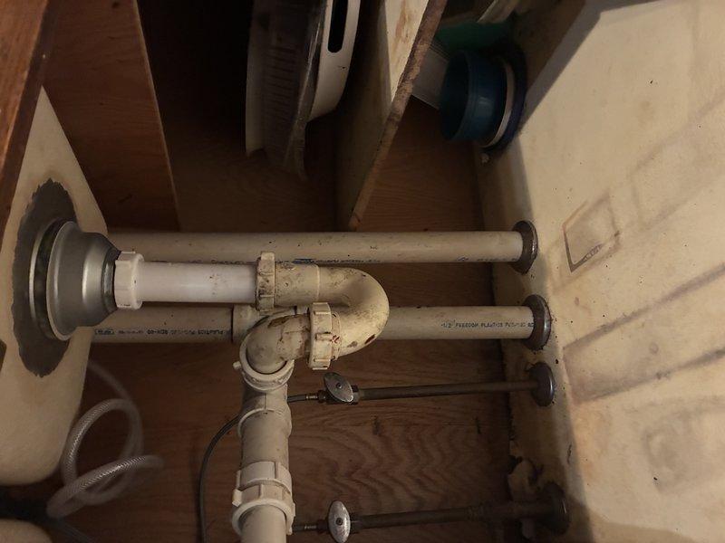 Conducted inspection of kitchen sink drain system. Examined stainless steel sink basin and identified normal wear with minor scratches and water marks. Inspected under-sink PVC plumbing configuration, noting slightly discolored P-trap showing signs of age. No immediate issues requiring repair were identified during this service visit.