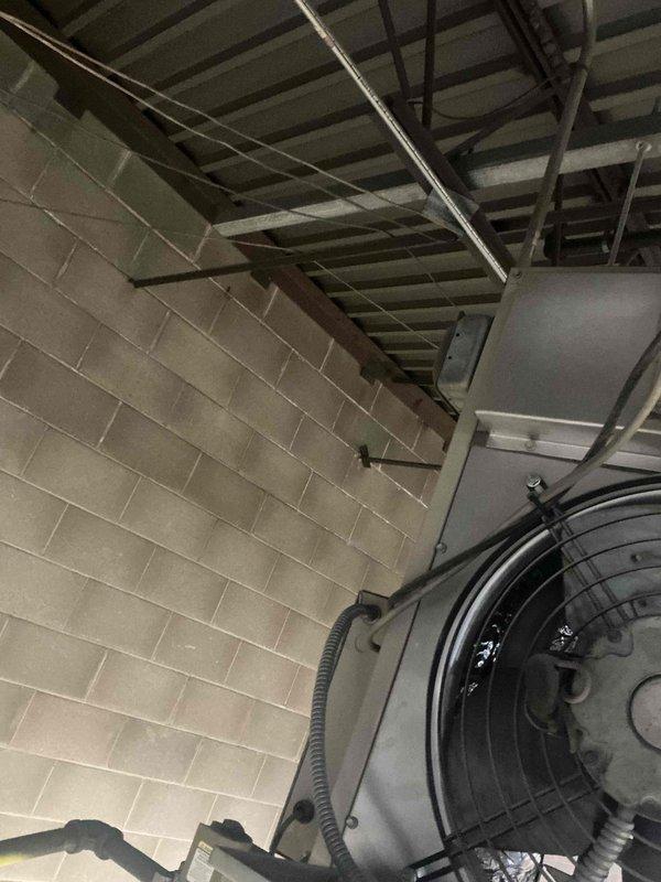 Conducted site assessment of commercial facility to evaluate gas line requirements for HVAC system installation. Inspected mechanical room with exposed ceiling structures and existing fan assembly. Examined concrete block wall construction to determine optimal routing path for new gas line installation and connection points to proposed equipment.