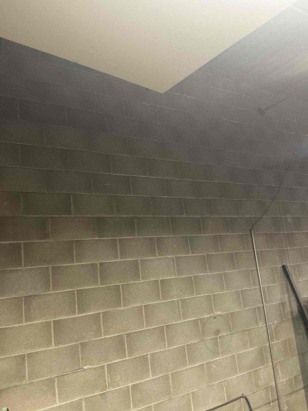 Conducted site assessment of commercial facility to evaluate gas line requirements for HVAC system installation. Inspected mechanical room with exposed ceiling structures and existing fan assembly. Examined concrete block wall construction to determine optimal routing path for new gas line installation and connection points to proposed equipment.