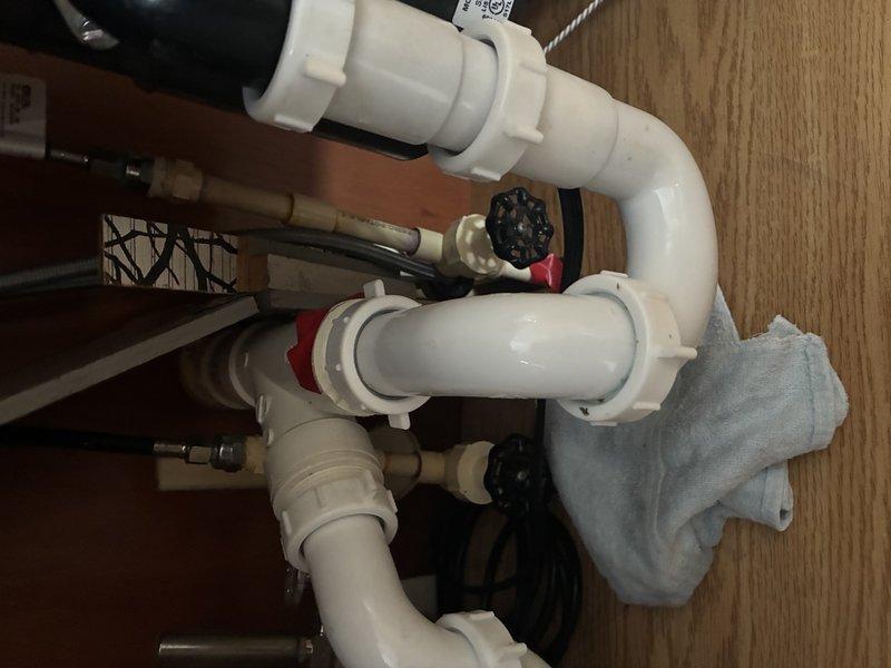Performed comprehensive inspection of bathroom plumbing components including examination of metal water supply line with shutoff valve connected to porcelain fixture. Inspected under-sink drainage system consisting of PVC pipes, joints, and water flow control valves for proper function and potential leaks. All components appeared functional with no active leaks detected, though minor aging observed on metal surfaces.