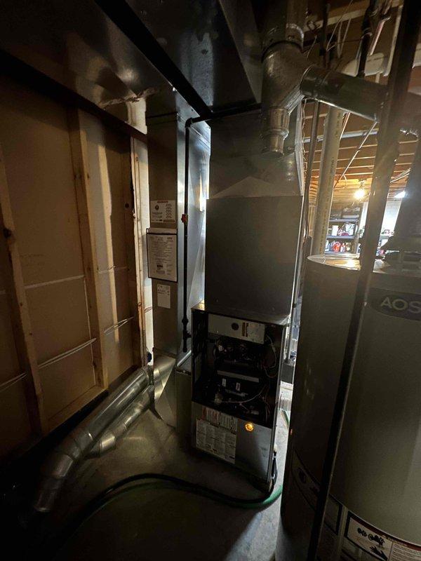 Conducted comprehensive inspection of existing HVAC system in basement utility area, focusing on furnace/air handler unit showing signs of deterioration. Documentation included detailed assessment of the aging central unit, connected ductwork system, and integration with existing water heater. Recommended full system replacement based on observed wear of internal components, control systems, and outdated specification parameters.