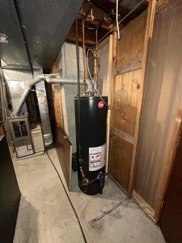 Conducted inspection of residential HVAC system in basement utility area. Existing setup includes furnace/air handler with connected ductwork, alongside water heater with copper piping. System appears functional but evaluation performed for potential replacement options based on age and efficiency considerations.