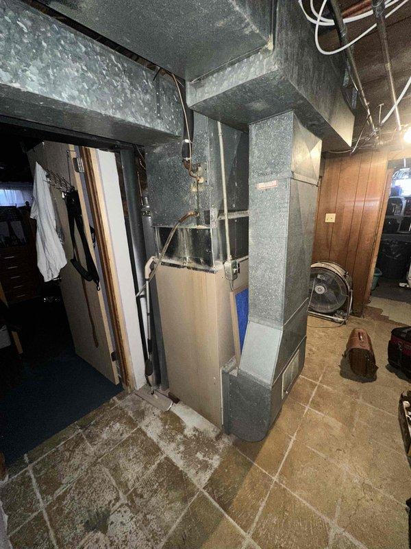 Conducted site evaluation for HVAC replacement at residential property. Current system shows age-related deterioration with insufficient insulation on existing ductwork in basement mechanical room. Exterior assessment revealed snow-covered condenser unit with protective cage that will require replacement. Recommended full system replacement including new energy-efficient air handler, properly insulated ductwork, and appropriately sized condenser unit with modern refrigerant standards.