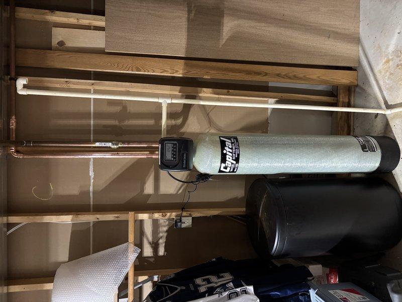Successfully installed an Envirotec water filtration/softening system in the utility area, including the main cylindrical tank with digital control panel and secondary brine tank. Completed all necessary plumbing connections with both copper and PVC piping, ensuring proper integration with the home's existing water system.