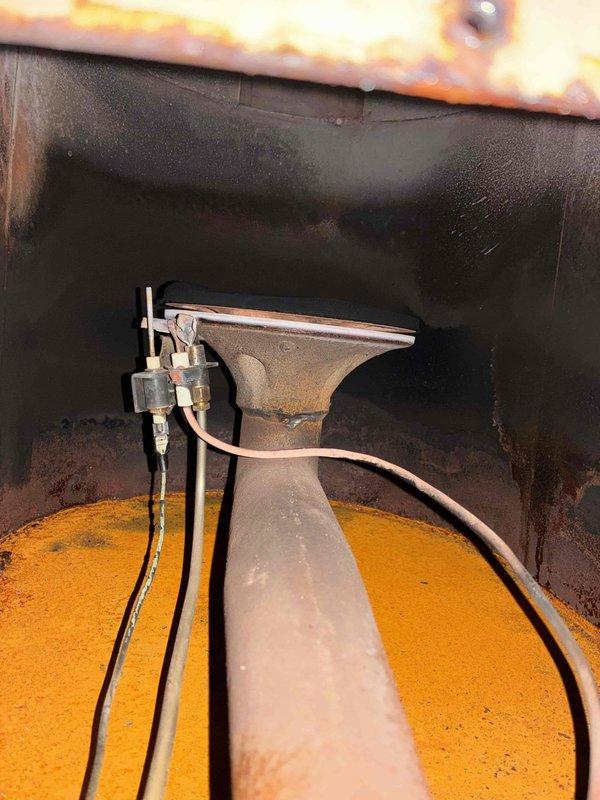 Inspected 10+ year old system with no heat complaint. Discovered severe internal corrosion and rust damage to heat exchanger and major components. Photos documented extensive oxidation on metal surfaces, deteriorated housing with holes, and significant rust accumulation at unit base. Determined heat exchanger has failed completely, creating unsafe operating conditions. Recommended immediate system replacement due to safety concerns and irreparable condition of critical components.