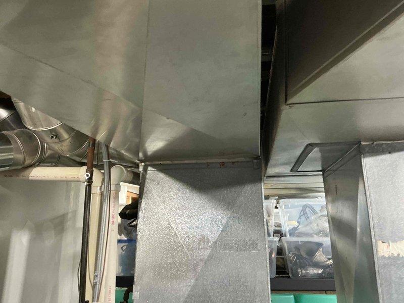 Completed inspection of commercial HVAC system with focus on ductwork configuration and outdoor condenser unit. Documented extensive snow accumulation completely covering the outdoor unit positioned against brick wall, potentially compromising proper airflow and operation. Recommended replacement of system to ensure reliable operation and prevent future service disruptions during severe winter conditions.