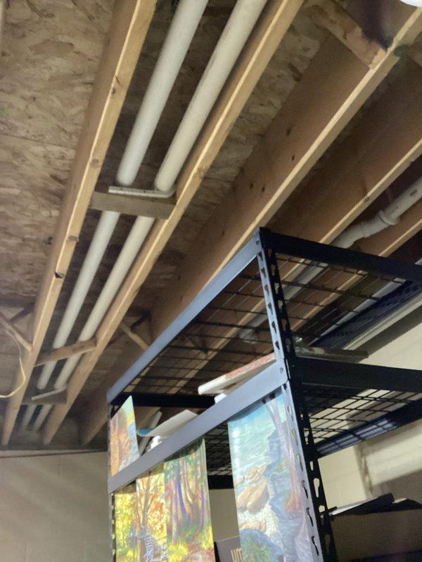 Conducted routine HVAC tune-up in unfinished basement utility area. Inspected exposed ductwork and ventilation system running between wooden joists. Verified system installation is properly leveled using precision measuring tools, with particular attention to electrical connections and component alignment.