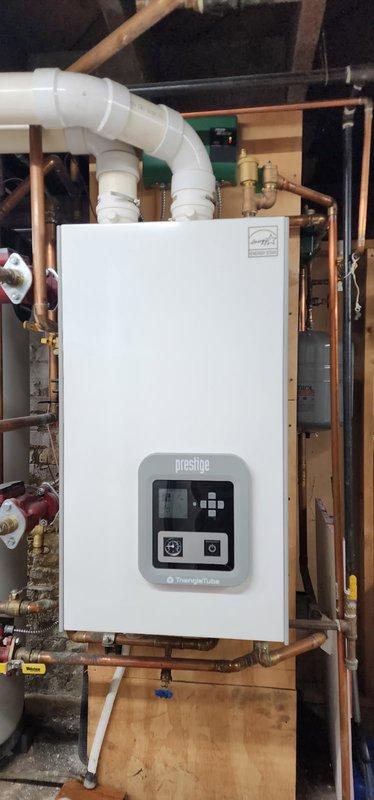 Conducted inspection of Triangle Tube Prestige boiler system. Pressure gauge reading was verified at approximately 1.1 bar (15 psi), confirming proper system pressure within normal operating range. Visual inspection of all connected PVC venting and copper supply lines revealed no leaks or irregularities.