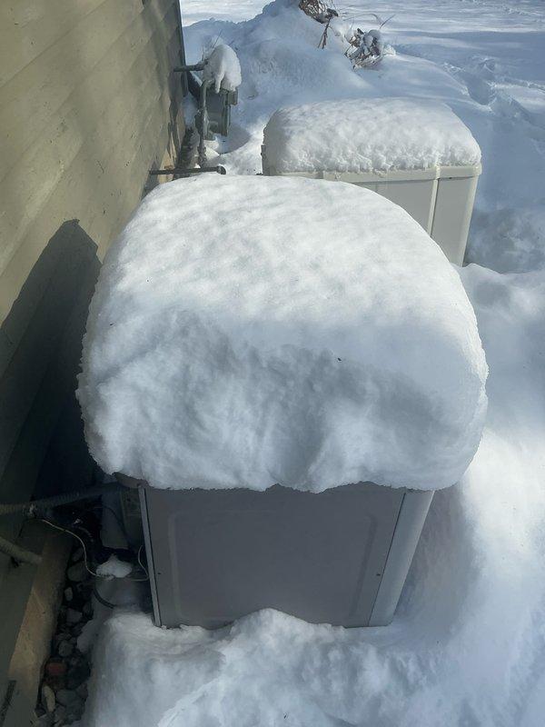 Inspected residential HVAC system consisting of a Carrier furnace in basement utility area and two outdoor heat pump units. Documented snow accumulation on exterior units which may affect proper ventilation and operation. System appears to include a 3-ton capacity based on markings on the galvanized ductwork. Interior installation includes PVC ventilation piping and standard connections with no visible damage.