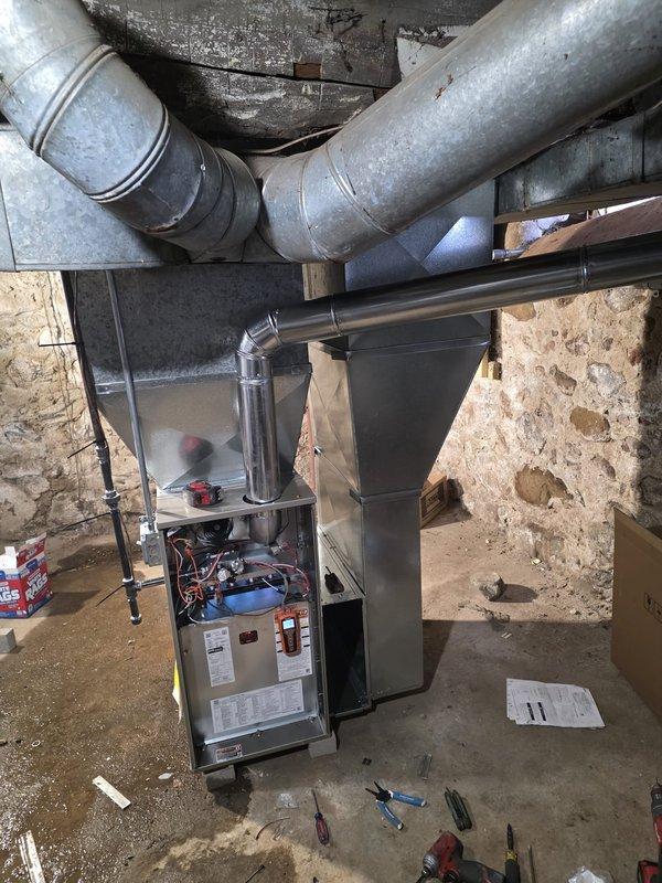 Successfully completed installation of a new furnace with proper connection of all ductwork and electrical components. Installed system includes galvanized sheet metal ducting with sealed joints and a horizontal exhaust vent pipe. Final inspection confirmed proper wiring of control modules and all connections are secure with system functioning as designed.
