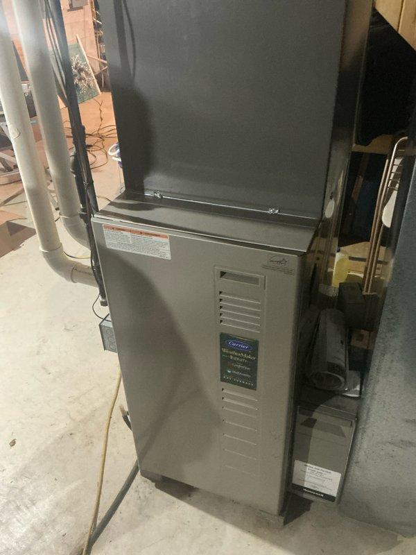 Performed inspection and assessment of Carrier WeatherMaker Infinity furnace system installation in basement utility area. Unit appears properly installed with connected ductwork, electrical wiring, and drainage system. Observed condensate drain with appropriate tubing configuration, though noted some water staining around drain area indicating possible previous drainage issues.