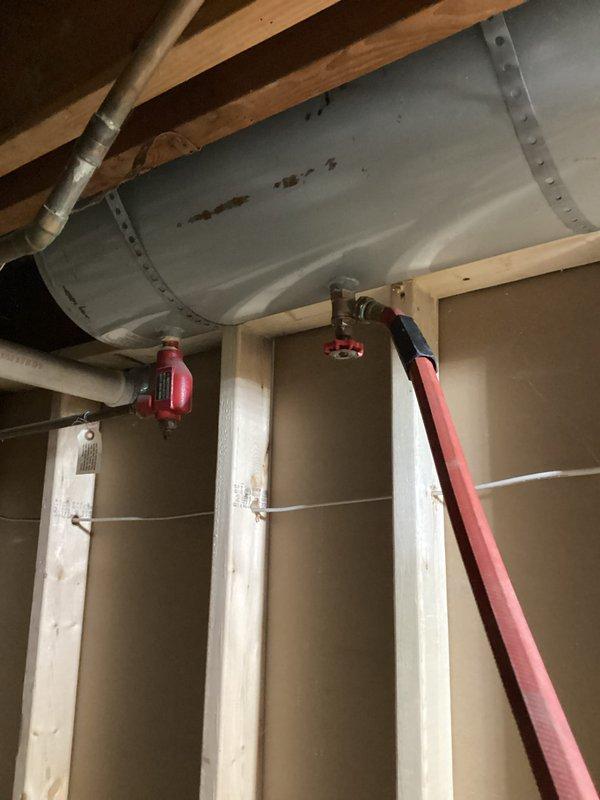 Inspected client's boiler system, noting pressure and temperature within acceptable range on Honeywell gauge. Evaluated exposed ductwork and associated red valve/control mechanism in partially finished mechanical area. System appears functional with minor surface discoloration on ductwork requiring no immediate attention.