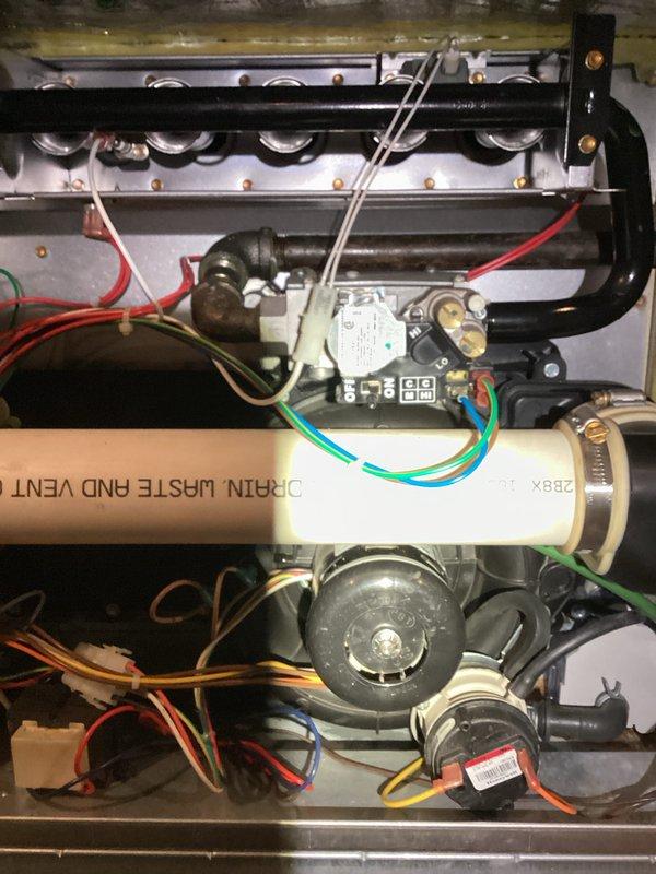 Performed inspection of furnace system revealing corrosion on drain pan and condensate components. Documented evidence of rust formation on metal housing near drainage assembly. Examined control board, electrical connections, and heat exchanger - all operational with no visible damage. Captured detailed photos of interior components for warranty documentation.