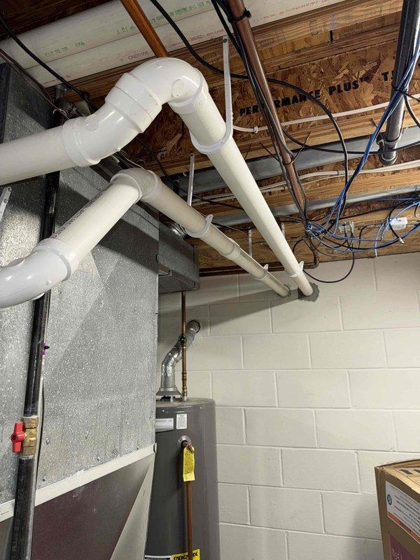 Performed inspection and evaluation of existing furnace (model SLP98UH090XV36C-04) in basement utility area. Documented infrastructure including water heater ventilation and ceiling-mounted PVC exhaust/intake piping system with multiple 90-degree joints. Noted proper installation of electrical connections including ground wire placement. Prepared comprehensive replacement estimate for customer review.