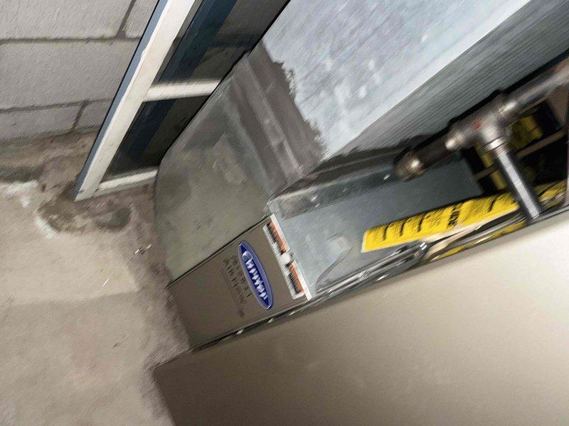 Inspected existing Carrier HVAC system in basement utility area. Evaluated current ductwork configuration, including metal ducts with foil insulation and PVC ventilation components. Documentation photos taken of the unit installation and surrounding mechanical infrastructure to prepare comprehensive replacement estimate.