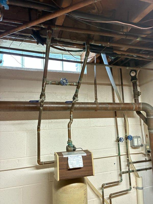 Conducted comprehensive inspection of residential water treatment system. System consists of primary cylindrical filtration tank with control head, connected to house plumbing via copper pipe network with multiple control valves. Identified aging copper pipes showing significant patina and potential corrosion points at critical junctions that may require future attention.