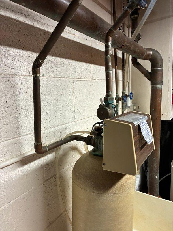 Conducted comprehensive inspection of residential water treatment system. System consists of primary cylindrical filtration tank with control head, connected to house plumbing via copper pipe network with multiple control valves. Identified aging copper pipes showing significant patina and potential corrosion points at critical junctions that may require future attention.