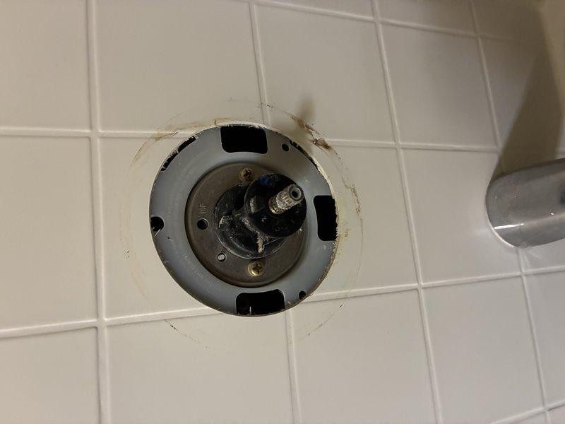 Inspected and diagnosed shower valve system showing significant corrosion and mineral buildup. Documented damaged cartridge mechanism with visible wear on mounting components. Recommended complete valve replacement to address potential water pressure issues and prevent future leaks. Current installation shows evidence of water damage around escutcheon plate.
