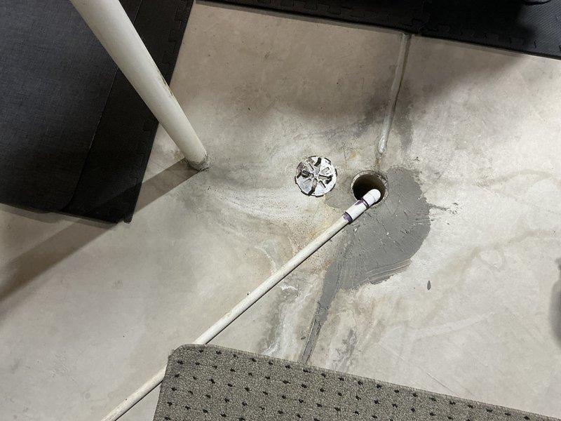 Conducted inspection of a residential HVAC system for potential replacement. Documentation included assessment of the current unit installed in basement/utility area with exposed wood framing, along with examination of existing plumbing connections and drainage system. Identified concrete floor drain infrastructure that would accommodate new system installation.