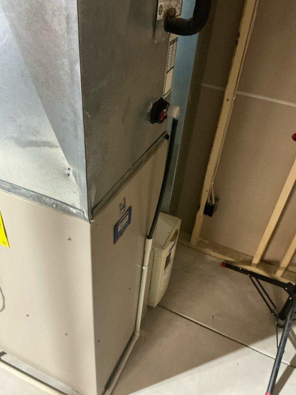 Conducted inspection of a residential HVAC system for potential replacement. Documentation included assessment of the current unit installed in basement/utility area with exposed wood framing, along with examination of existing plumbing connections and drainage system. Identified concrete floor drain infrastructure that would accommodate new system installation.