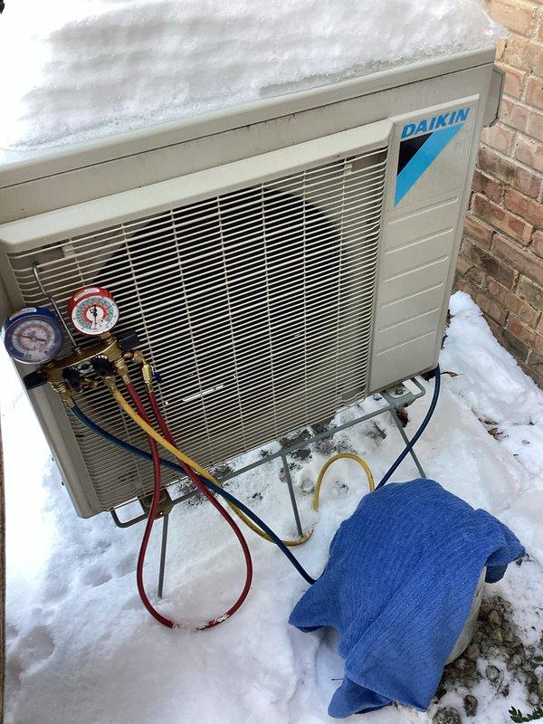 Responded to no heat complaint on Daikin mini-split system. Inspected indoor wall-mounted head unit and outdoor condensing unit which was covered with snow. Connected gauge set to verify refrigerant pressures and performed system diagnostic. Cleared snow accumulation from around outdoor unit to restore proper airflow, allowing system to resume normal heating operation.