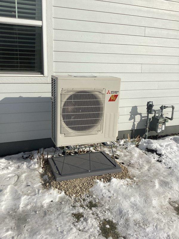 Completed installation of a Mitsubishi mini-split heat pump system featuring outdoor condensing unit properly mounted on a concrete pad adjacent to customer's residence. Connected all refrigerant lines with proper insulation and installed electrical disconnect box on exterior wall according to manufacturer specifications and local codes.