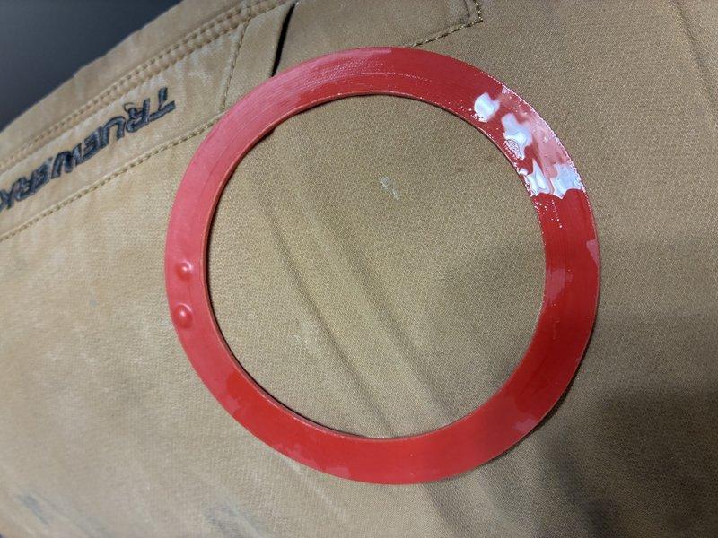 Replaced worn toilet tank seal with new red rubber gasket to resolve leaking issue between tank and bowl. Photographed replacement part prior to installation. All fixtures now functioning properly with no leaks observed during testing.