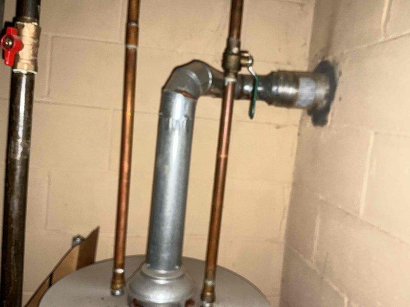 Conducted assessment for HVAC system replacement in basement utility area. Inspection revealed existing water heater with multiple copper supply lines and galvanized vent pipe against cinder block wall. Evaluated current HVAC setup with insulated ductwork, furnace unit, and PVC condensate drainage system. Photos documented mechanical configurations to support replacement estimate proposal.