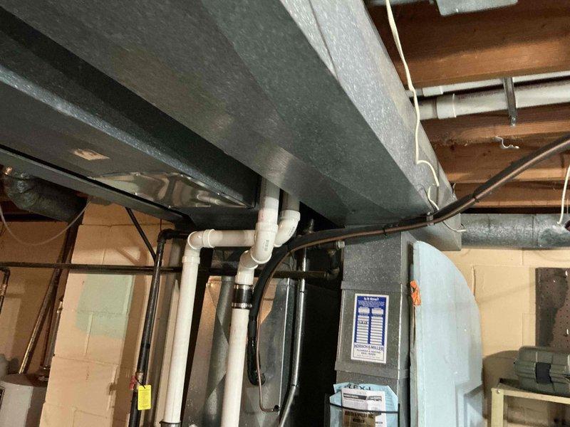 Conducted assessment for HVAC system replacement in basement utility area. Inspection revealed existing water heater with multiple copper supply lines and galvanized vent pipe against cinder block wall. Evaluated current HVAC setup with insulated ductwork, furnace unit, and PVC condensate drainage system. Photos documented mechanical configurations to support replacement estimate proposal.