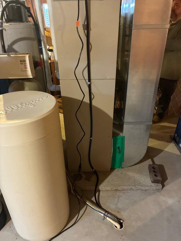 Installed and configured an AprilAire humidifier system with digital control panel displaying current humidity level (51%). The control unit was mounted on the HVAC system with proper wire connections (yellow, red, and blue) established. System includes "Service Required" and "Humidifier On" indicator functionality and was properly integrated with the existing furnace and ductwork in the basement utility area.