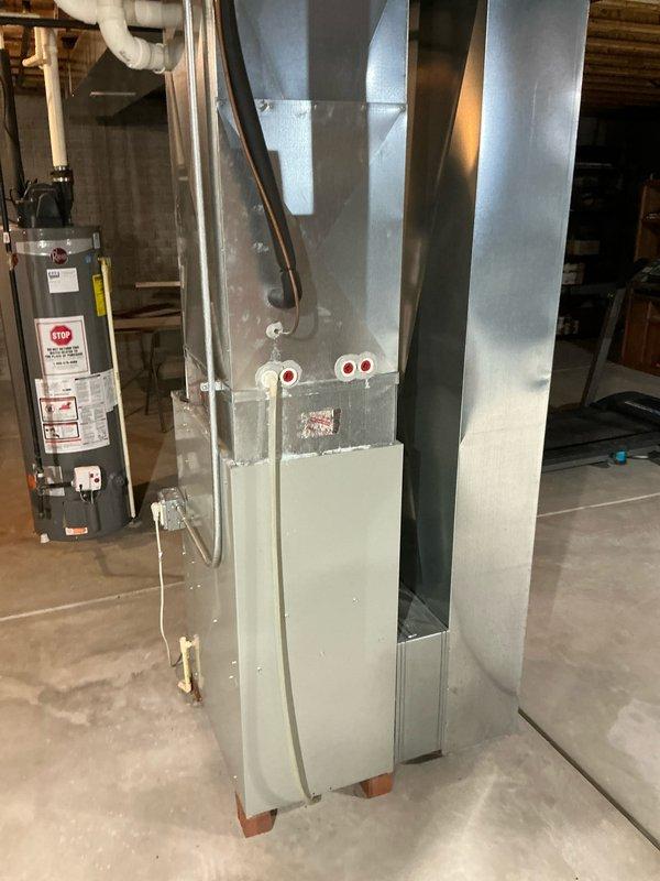 Completed installation of a new furnace system in residential basement, including proper connection to existing ductwork and water heater. System features dual PVC vent pipes exiting through exterior wall and a protected outdoor unit. All components were properly installed according to manufacturer specifications and tested for optimal performance.