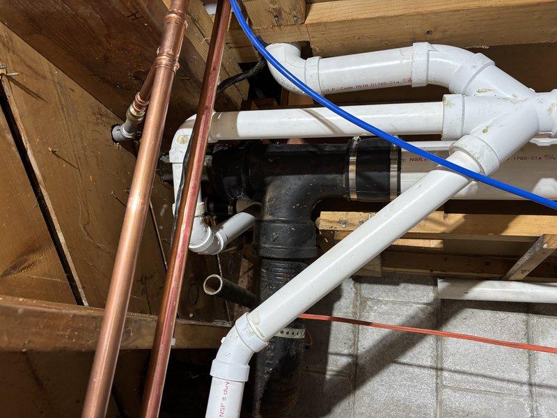 Inspected extensive copper supply line and PVC drainage system in unfinished basement area. Documented the condition of the plumbing infrastructure, noting some aging and discoloration on copper pipes. Verified proper installation of waste stack with supporting clamps and confirmed all connections were secure with no active leaks.