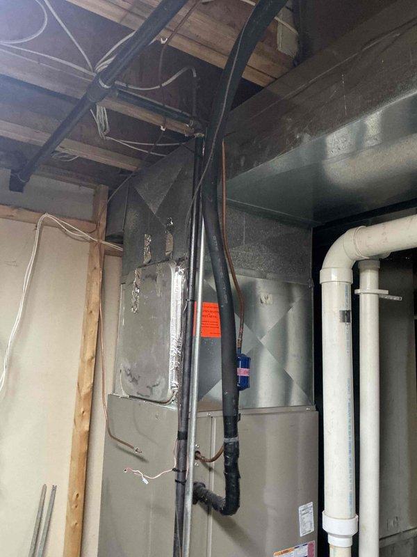 Conducted comprehensive IAQ assessment of residential HVAC system located in utility area with particular attention to furnace unit and associated ductwork. Documented existing installation configuration including black insulated pipes and PVC drainage components. Evaluation revealed current system has standard efficiency specifications with potential for improved indoor air quality through recommended upgrades.