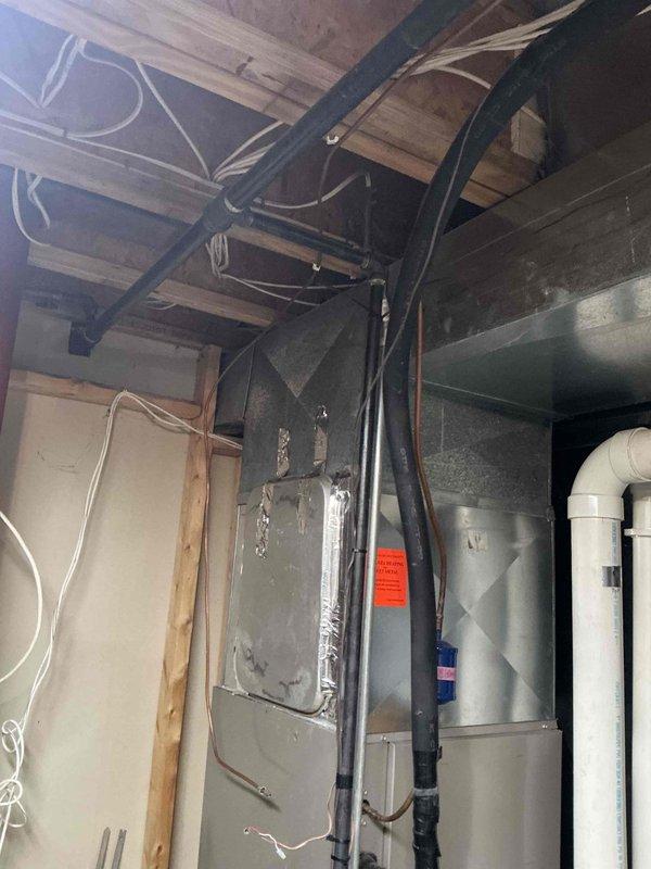 Conducted comprehensive IAQ assessment of residential HVAC system located in utility area with particular attention to furnace unit and associated ductwork. Documented existing installation configuration including black insulated pipes and PVC drainage components. Evaluation revealed current system has standard efficiency specifications with potential for improved indoor air quality through recommended upgrades.