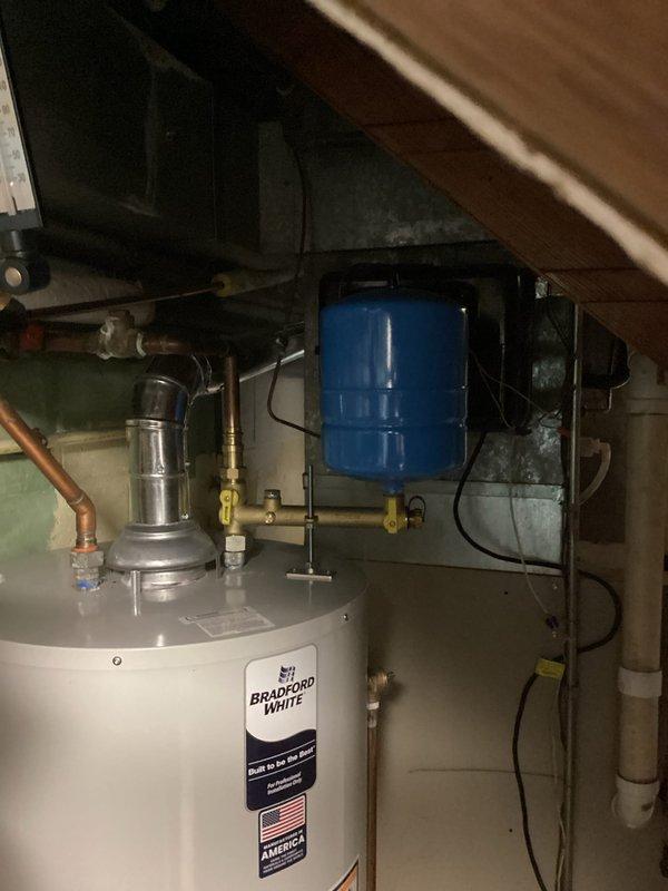 Installed a complete residential hot water system including a Bradford White water heater with proper venting, copper supply lines, and PVC drain connections. System includes a wall-mounted blue expansion tank with appropriate valves, thermometer, and brass fittings to ensure optimal pressure regulation and temperature control.