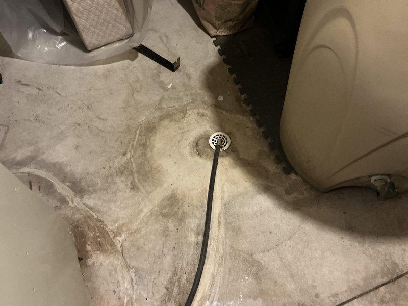 Conducted inspection of existing HVAC system requiring replacement. Documented water damage around floor drain in utility area indicating potential drainage issues. Observed exterior condenser unit properly winterized with protective plastic covering. Recommended complete system replacement to address water damage concerns and improve overall efficiency.