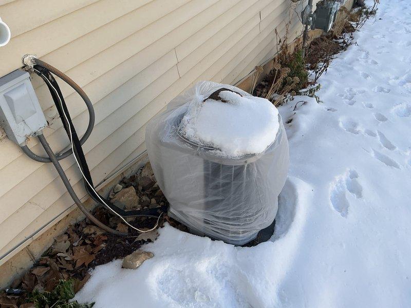 Conducted inspection of existing HVAC system requiring replacement. Documented water damage around floor drain in utility area indicating potential drainage issues. Observed exterior condenser unit properly winterized with protective plastic covering. Recommended complete system replacement to address water damage concerns and improve overall efficiency.