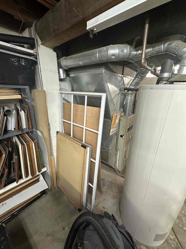 Completed inspection of residential HVAC system located in basement utility area. Documented existing furnace (WeatherMaker model) with connected ductwork, adjacent water heater, and water filtration system. Prepared estimate for complete system replacement due to age and condition of current equipment.