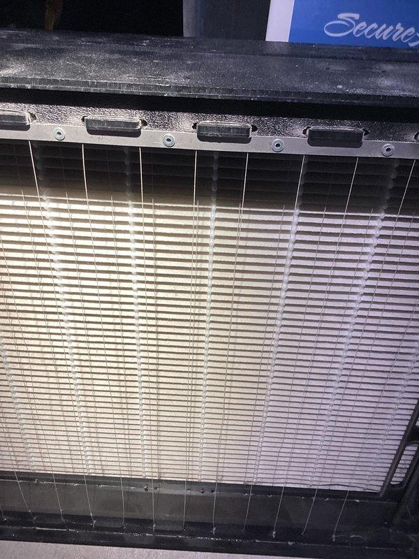 Conducted warranty service inspection of HVAC system, which included examination and documentation of air filtration components showing accumulation of particulate matter on the filter frame. Additionally, inspected and photographed exterior condensate drainage system, noting proper PVC elbow installation and confirming drainage path through foundation gravel, though observed some ice formation at discharge point that should be monitored during freezing conditions.