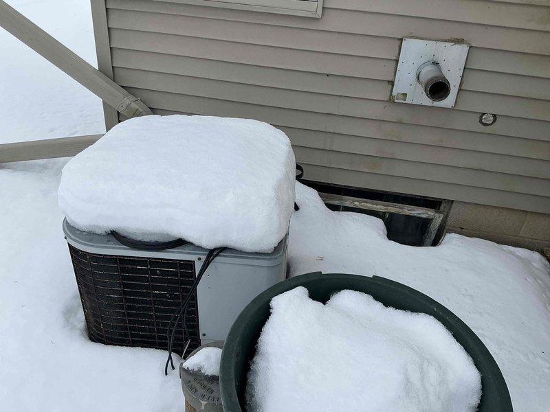 Conducted assessment of an aging HVAC system with identified outdoor condenser unit showing significant snow accumulation and potential exposure damage. Inspection of basement utility room revealed outdated furnace with deteriorating ductwork connections. Recommended full system replacement to improve energy efficiency and prevent potential failure during extreme weather conditions.