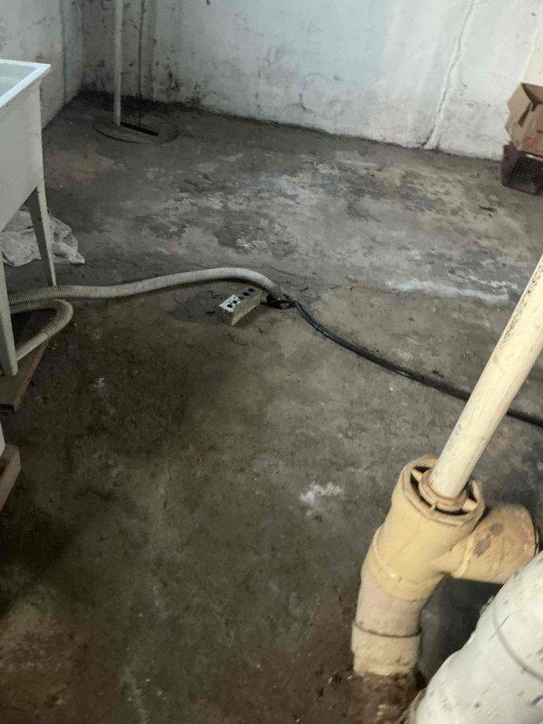 Conducted assessment of aging water heater installation in basement utility area showing signs of galvanic corrosion at copper/galvanized pipe connections. Noted significant water damage on concrete floor and walls, with visible staining and moisture issues. Recommended replacement of current system with modern unit to address corrosion issues and prevent potential water damage progression.