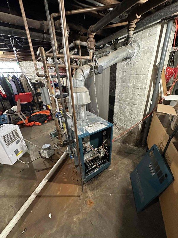 Conducted comprehensive inspection of existing HVAC system in unfinished basement area. Evaluated aging furnace unit showing signs of wear on internal components and wiring. Documented current installation conditions including ventilation configuration and potential replacement requirements for the complete system.