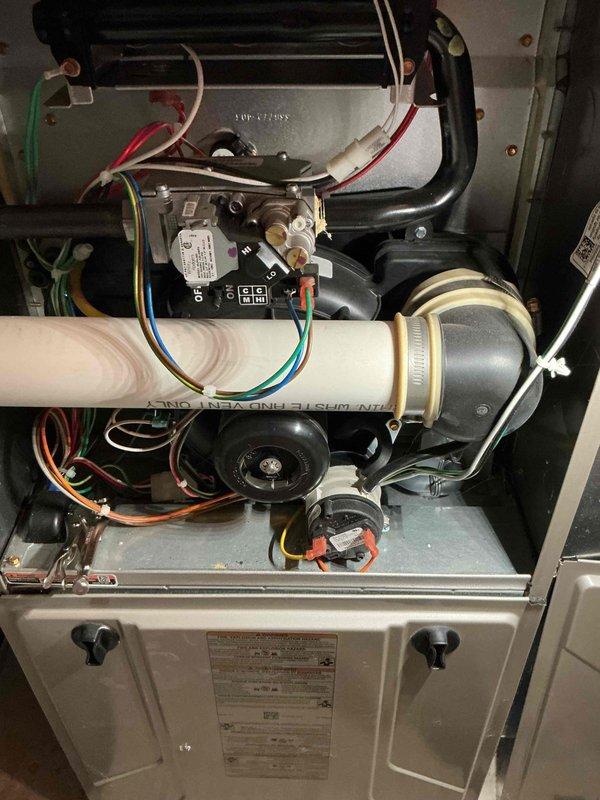 Performed routine HVAC tune-up service on existing furnace system. Inspected heat exchanger components and observed soot buildup in duct connections. Removed front panel to examine PVC exhaust pipe, draft inducer motor, control board, and wiring connections. All components were found in normal working condition with no signs of deterioration or leakage.