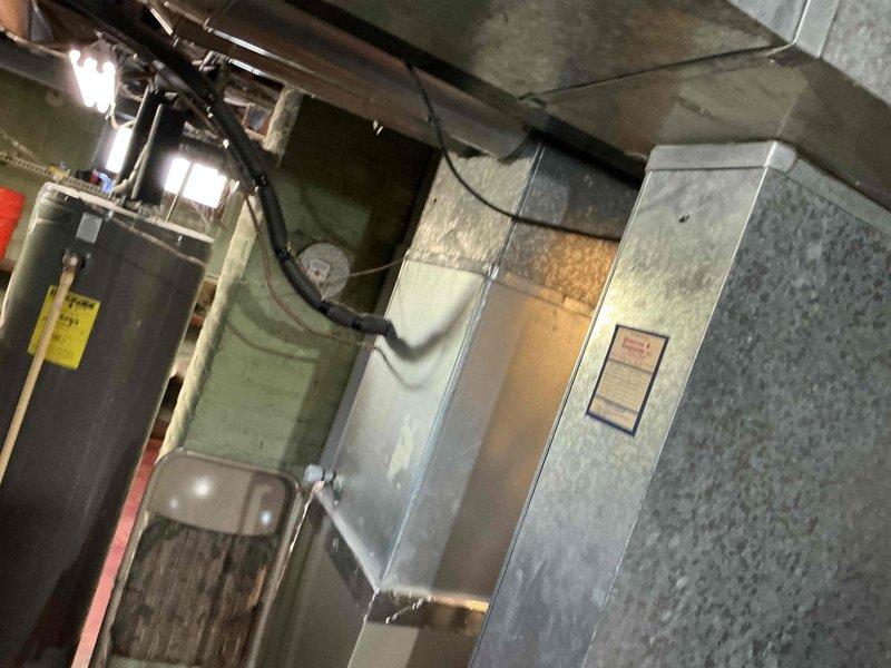 Conducted comprehensive assessment of existing HVAC system in basement utility area, documenting aging furnace/air handler unit with galvanized steel exterior alongside water heater. Evaluated current ductwork configuration including black flexible ducting and circular sections for replacement planning. Recommended complete system replacement due to equipment age and efficiency concerns.