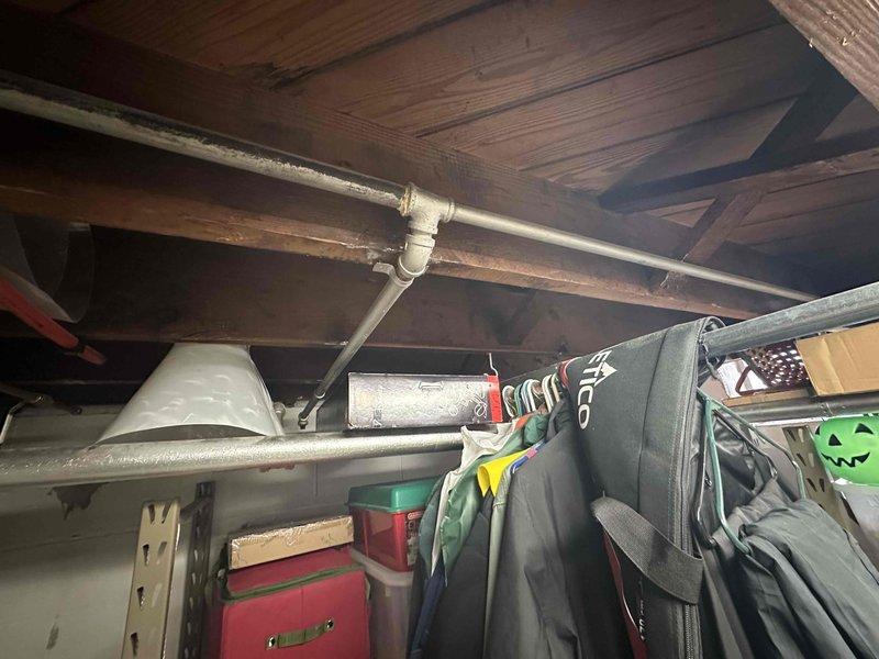 Conducted inspection of basement area housing existing HVAC infrastructure. Documented exposed ceiling joists, PVC piping configuration, and current water heater installation. Identified storage items requiring relocation prior to equipment replacement. Evaluated utility space layout for optimal new system placement considering existing ductwork and plumbing connections.