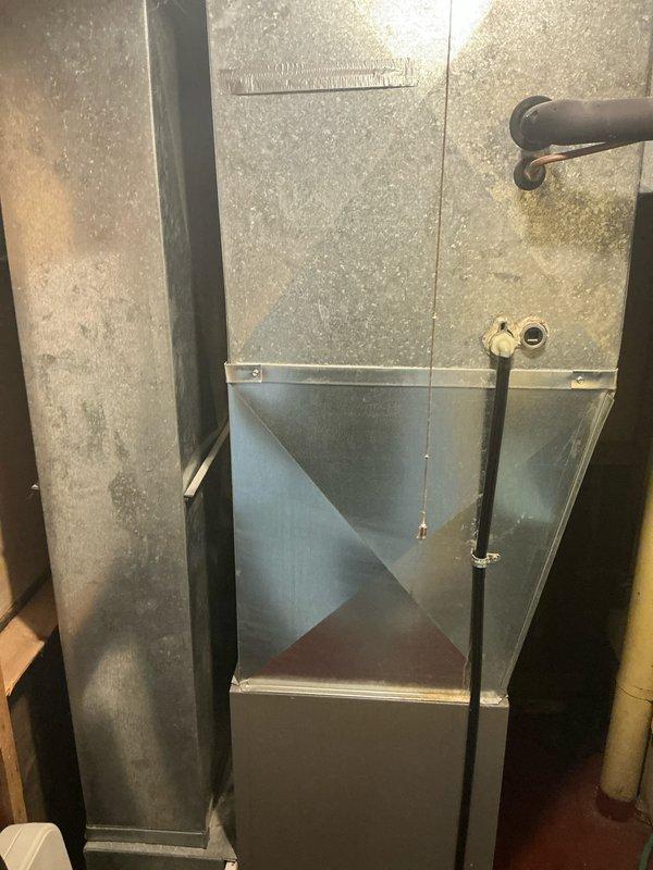 Conducted assessment of HVAC system located in basement utility area. Observed existing ductwork showing signs of age with accumulated dust on galvanized surfaces. Identified potential air quality concerns related to utility infrastructure routing, including electrical cables and PVC piping in close proximity to air handler. Recommended installation of enhanced filtration system to address indoor air quality issues.