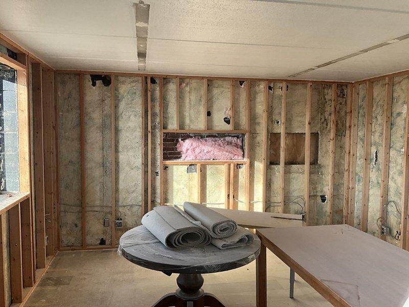 Conducted initial assessment of residential property requiring HVAC replacement. Inspected interior wall cavities with exposed framing and insulation to evaluate existing ductwork configuration and potential system integration challenges. Examined exterior building envelope to assess optimal location for outdoor unit placement, noting proper drainage considerations with existing downspout system.